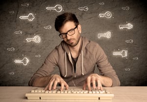 A young internet geek working online, hacking login passwords of social media users concept with glowing drawn keys on the wall