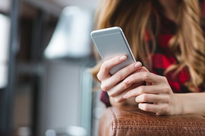 Close up of smartphone used by young blonde woman in plaid shirt